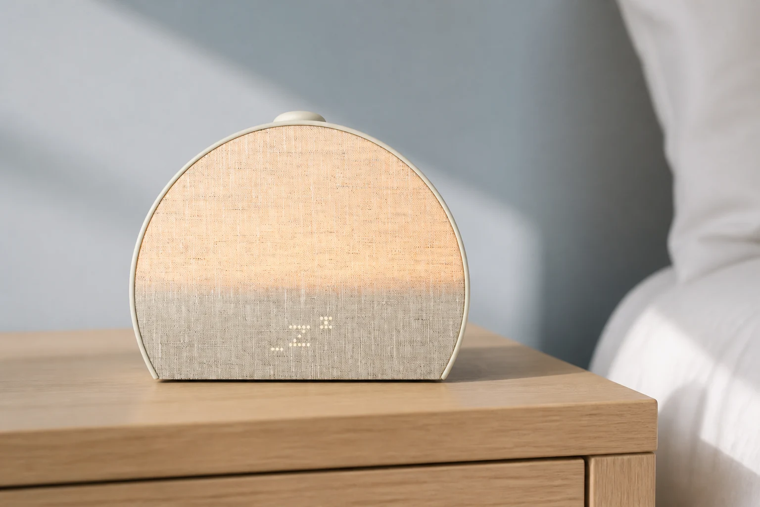 Hatch Sleep Clock: the adult model with contactless sleep tracking Hatch Sleep Clock in Putty on a light oak nightstand beside white bedding